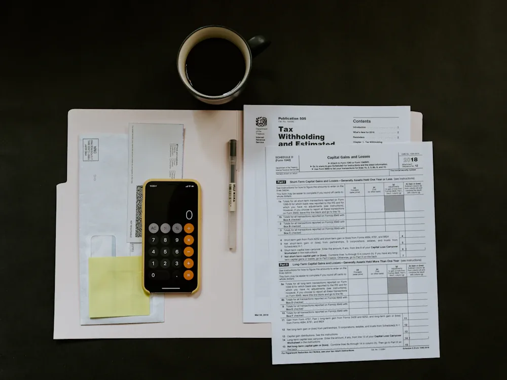 Formularios de impuestos, calculadora y café sobre un escritorio